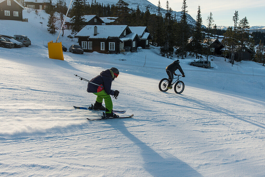 Radfahrer und Skifahrer wetteifern auf der Skipiste