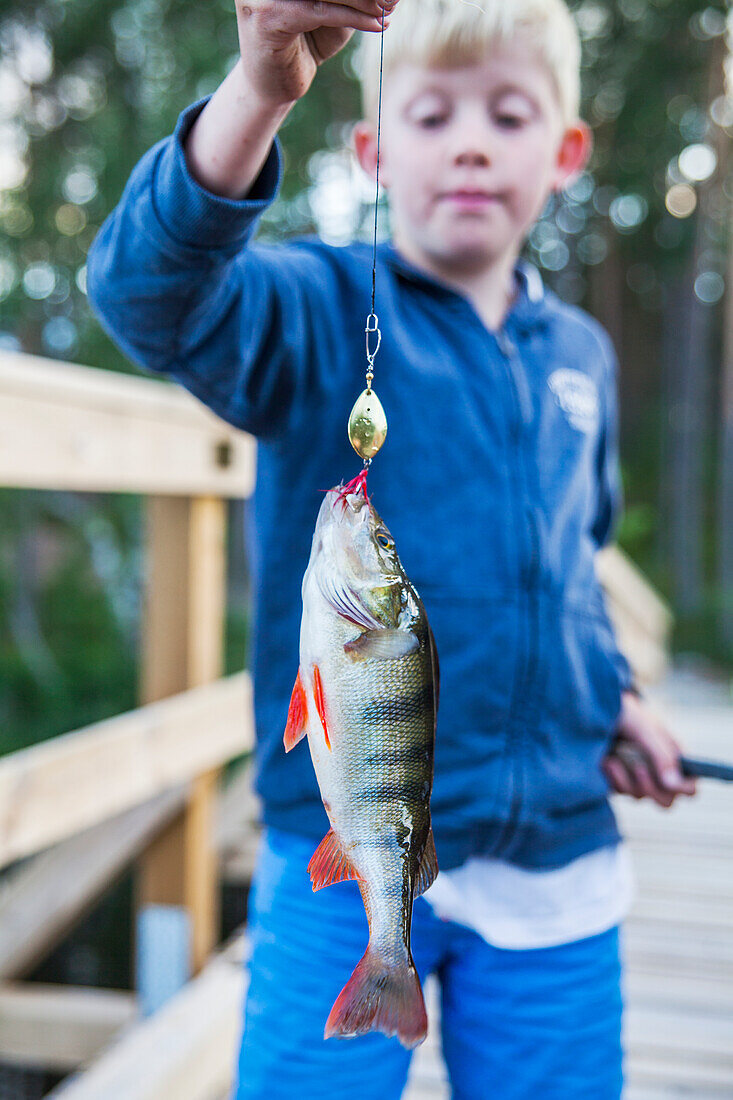 Junge hält gefangenen Fisch