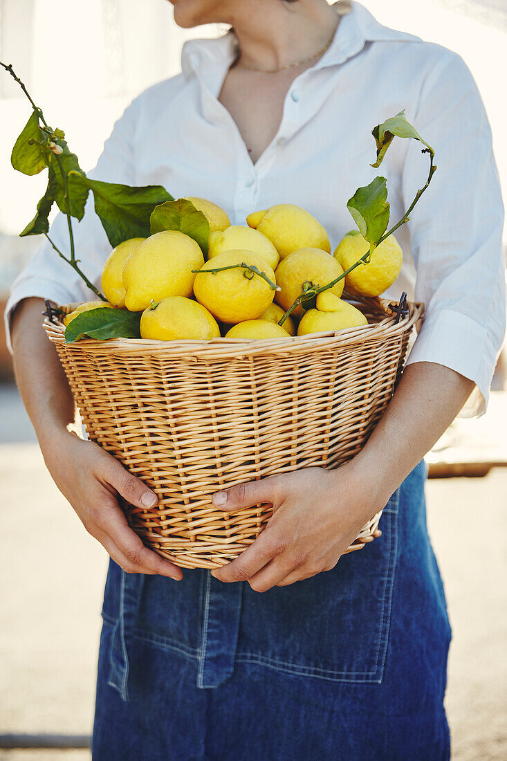 Frau hält Korb voller Zitronen