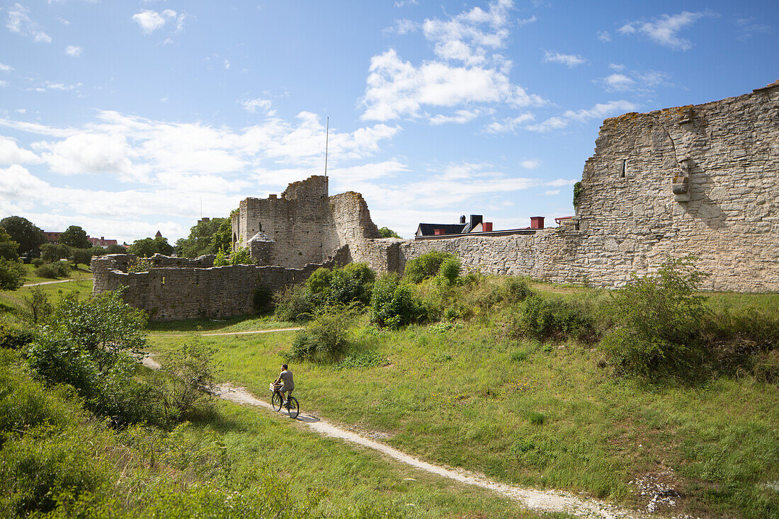 Man cycling along old ruins