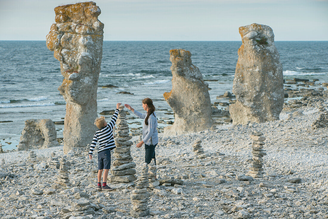 Mutter und Sohn stapeln Steine am Strand