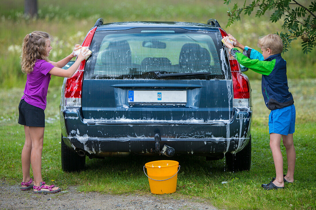 Junge und Mädchen waschen Auto