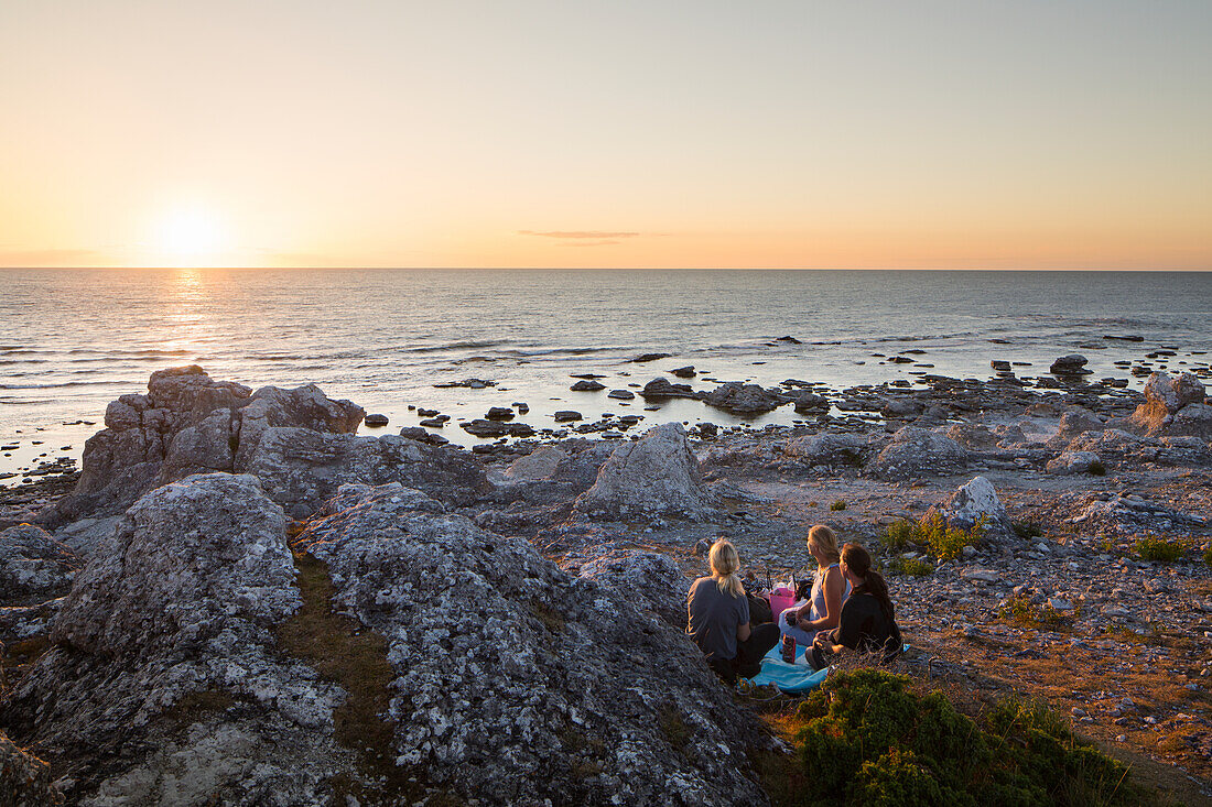 Young people watching sunset on beach