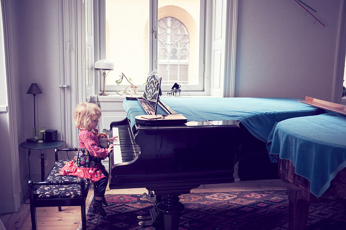 Kleines Mädchen spielt Klavier im Wohnzimmer
