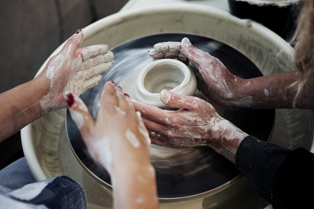 Close up of women making pot on potters wheel
