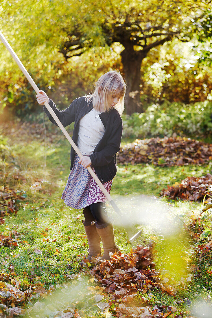 Girl raking leaves in garden