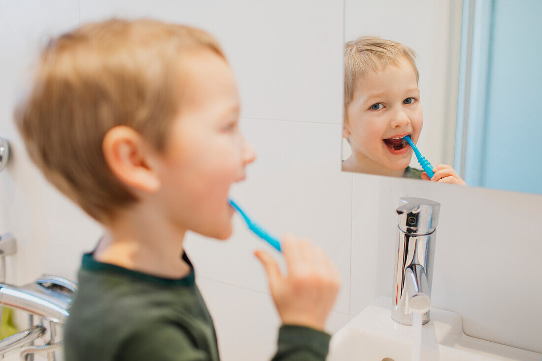 Reflection of boy brushing teeth