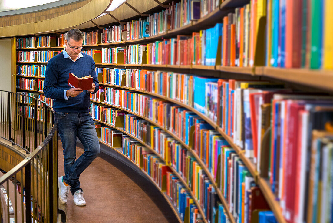 Mann liest ein Buch in der Bibliothek