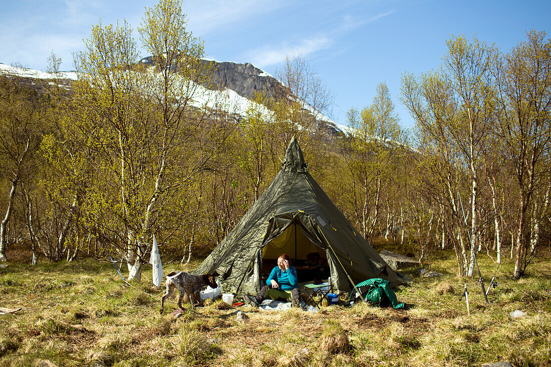 Woman and dog in front of tent