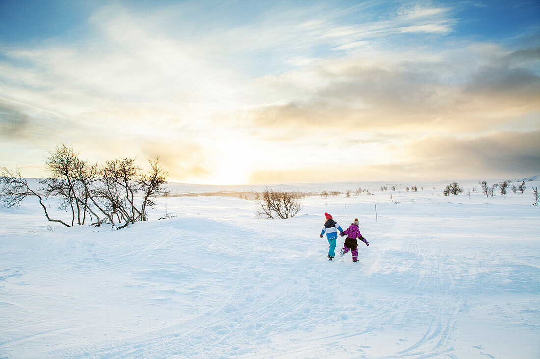 Bruder und Schwester rennen im Schnee