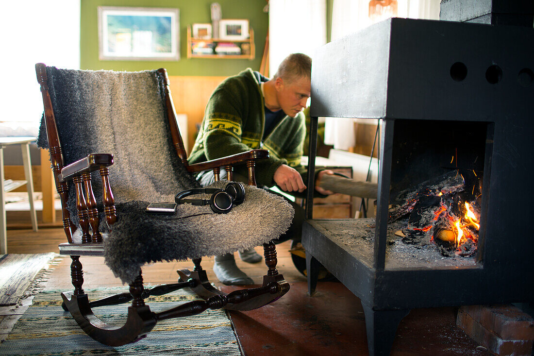 Man putting firewood into fireplace