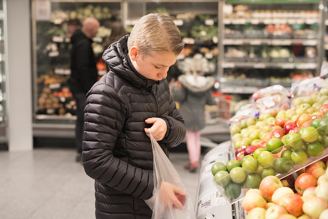Junge wählt Äpfel im Supermarkt aus