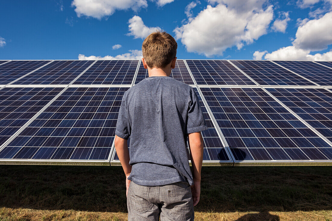 Boy standing in front of solar panels