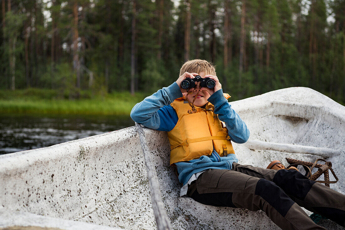 Boy on boat looking through binoculars
