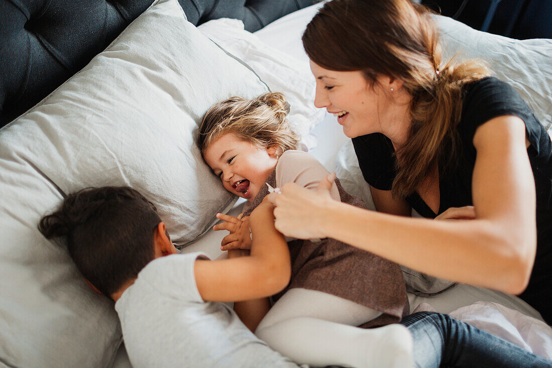 Mutter und Kinder spielen im Schlafzimmer