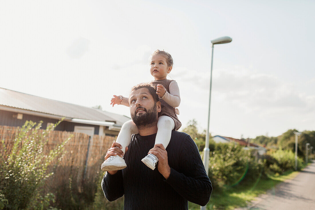 Father carrying daughter on shoulders