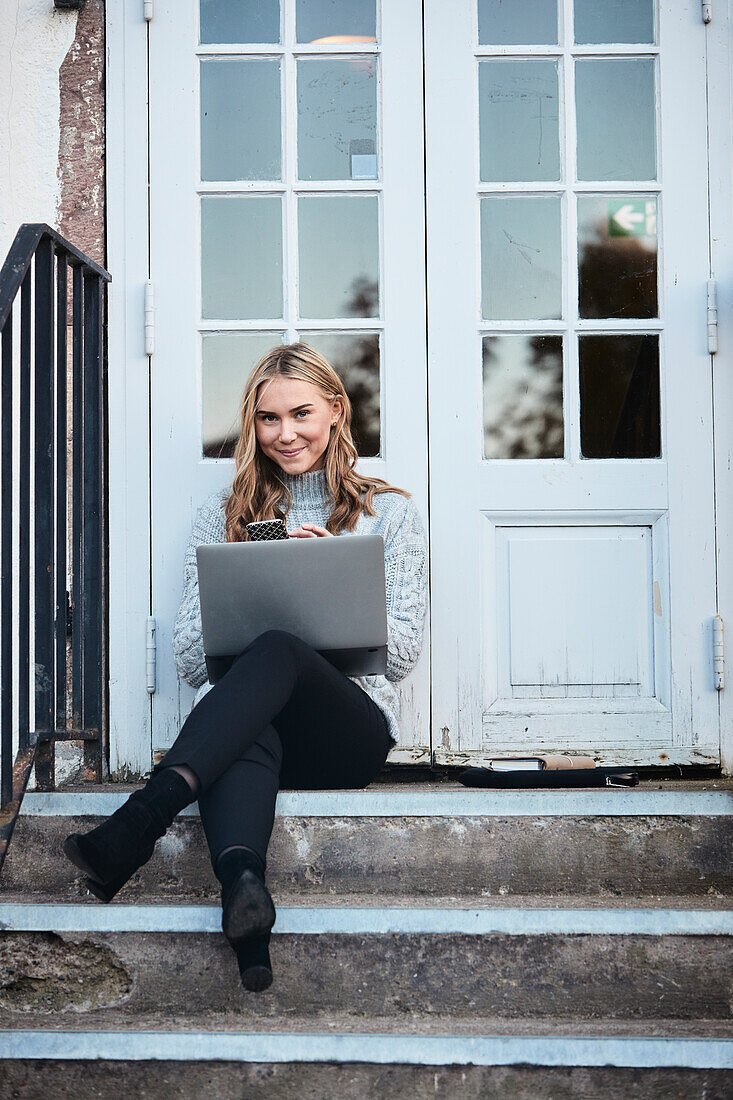 Woman using smartphone on front stoop