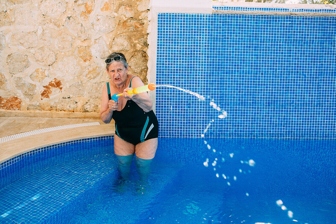 Woman with water pistol in swimming pool