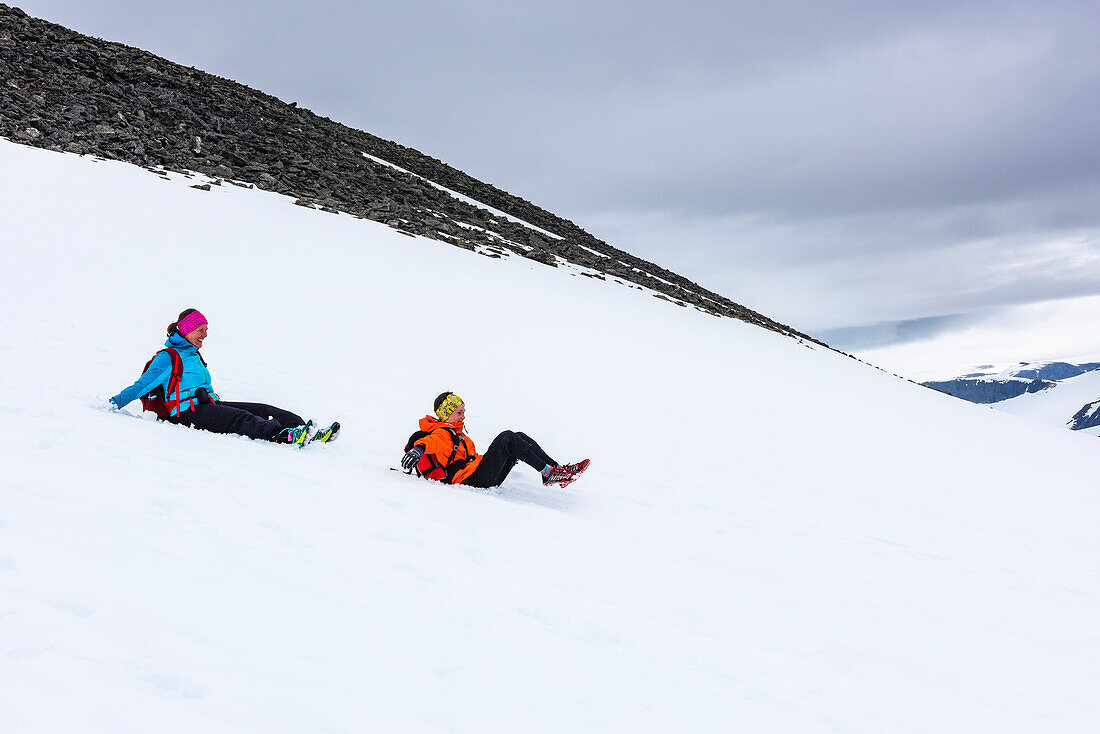 Woman and boy sliding on snow