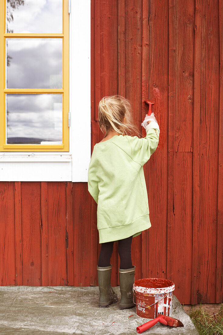 Mädchen malt Holzhaus