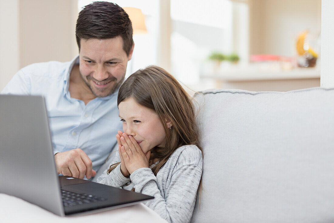 Vater mit Tochter benutzt Laptop zu Hause