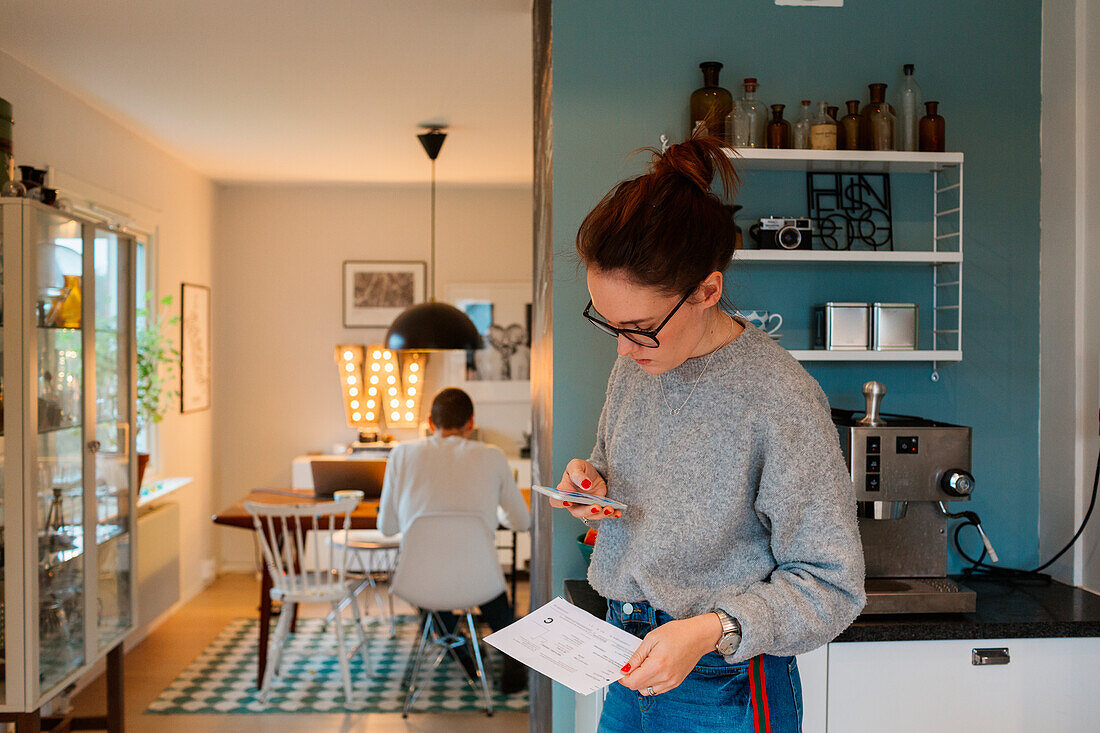 Young woman with smartphone in kitchen