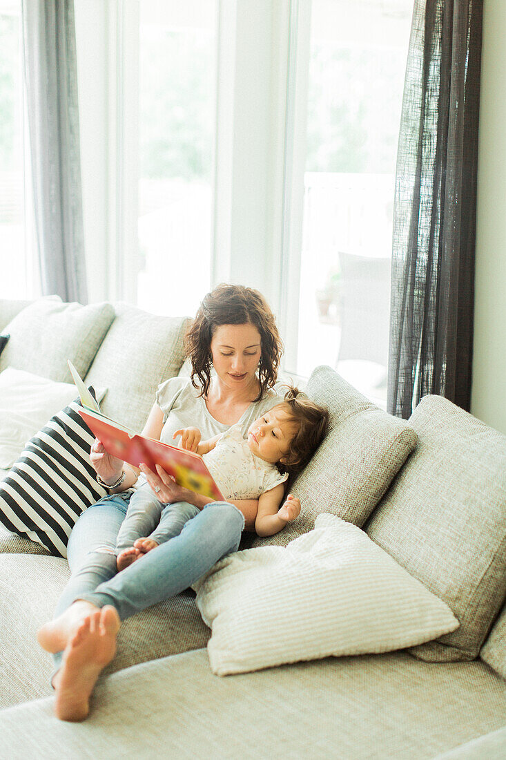 Mother reading childrens book with daughter