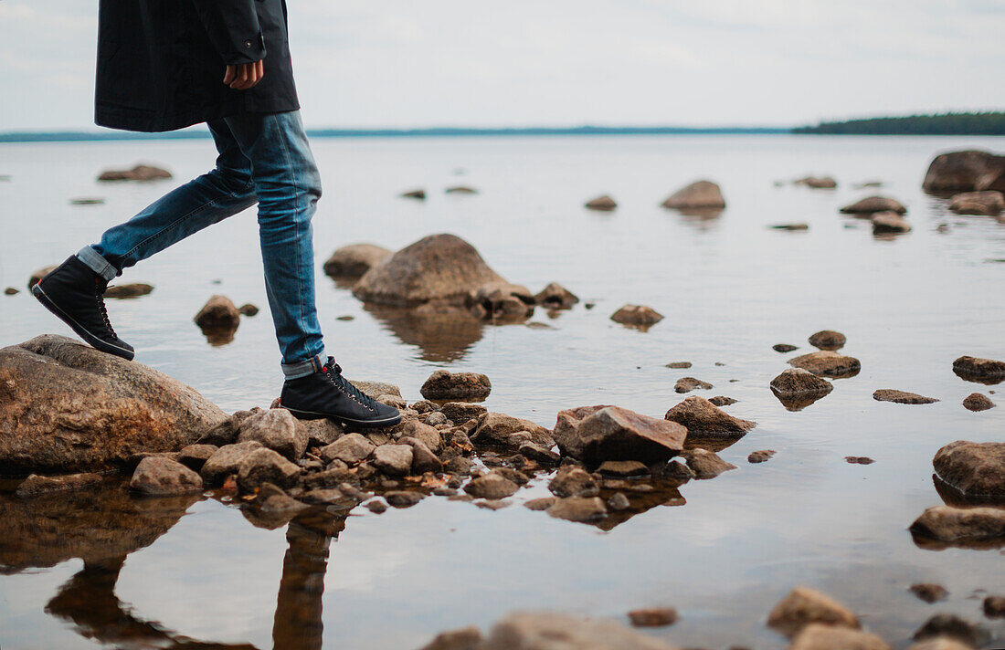 Young man walking on rocks in sea