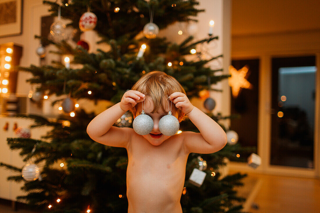 Junge spielt mit Weihnachtsschmuck