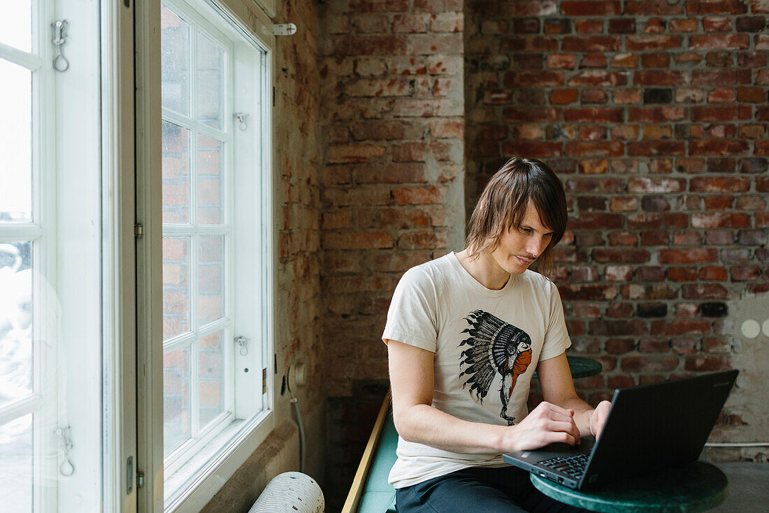 Junger Mann, der einen Laptop benutzt