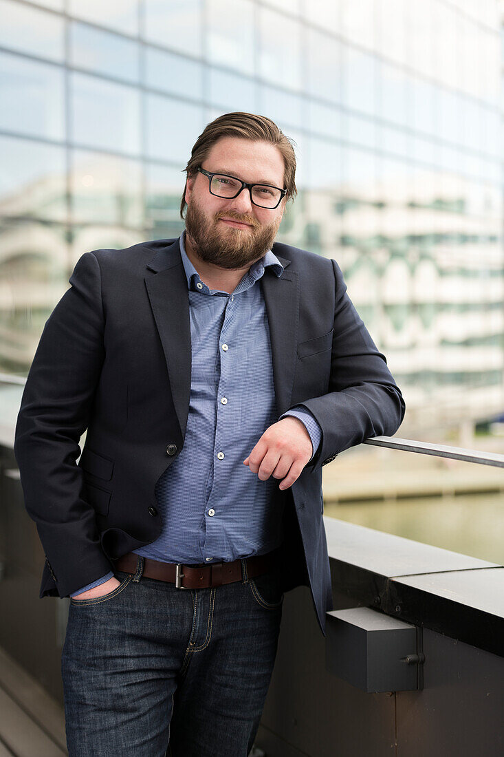 Lächelnder Mann steht auf Balkon