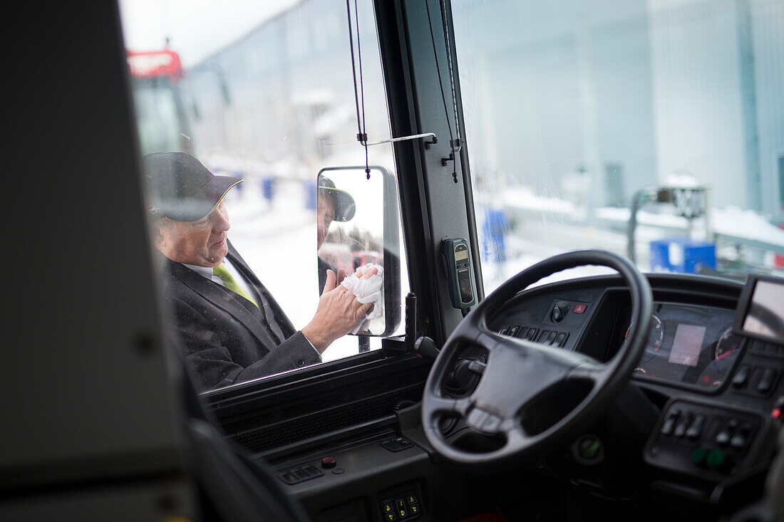Busfahrer reinigt Seitenspiegel