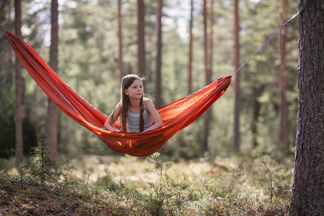 Teenage girl sitting in hammock in forest