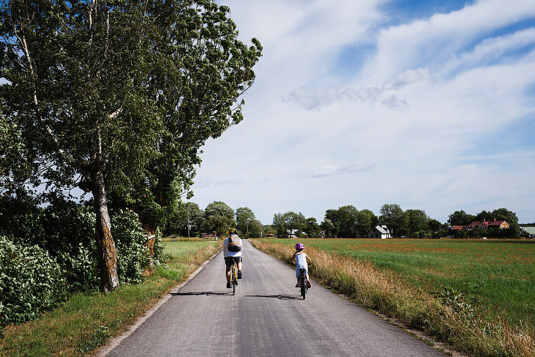 Vater und Tochter fahren mit dem Fahrrad über die Felder