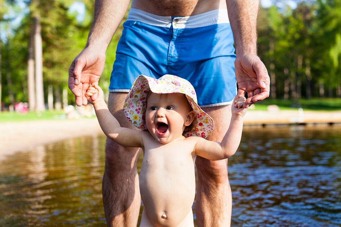 Father holding toddler at water