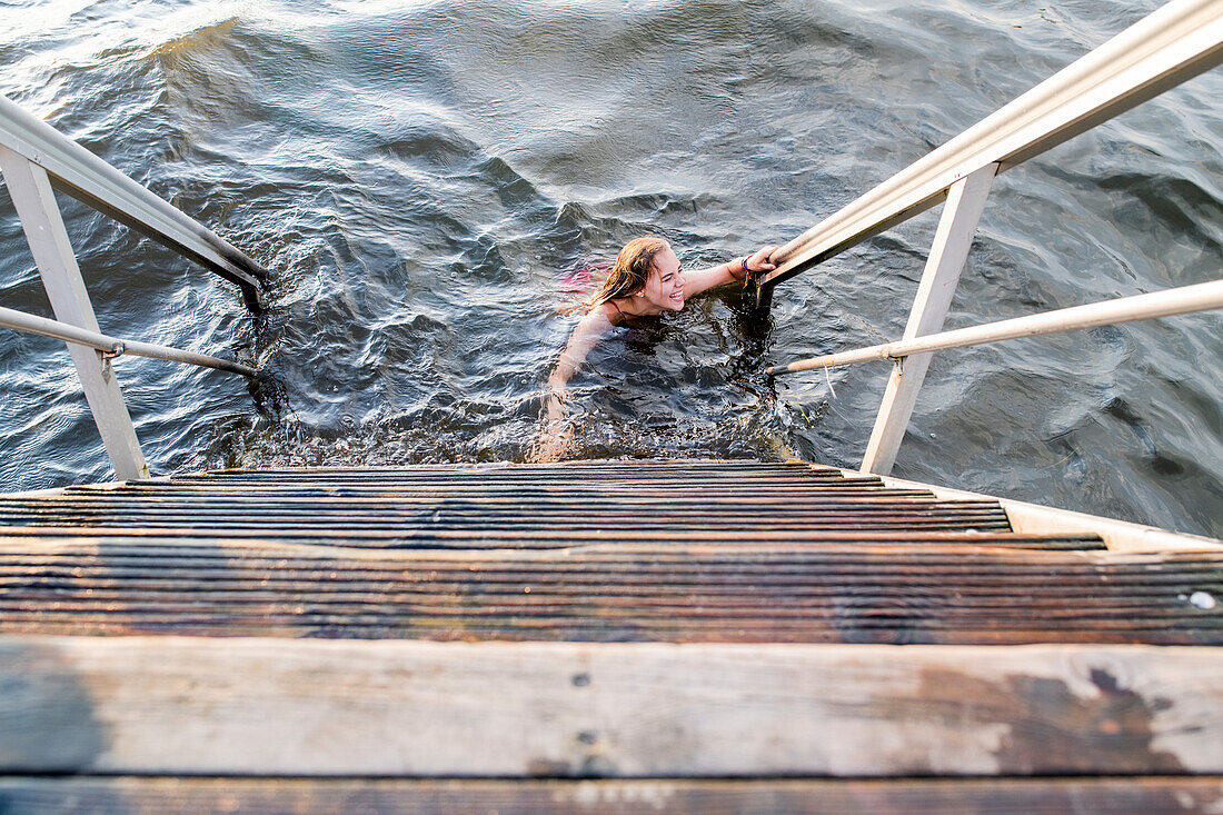 Woman swimming in lake next to wooden steps