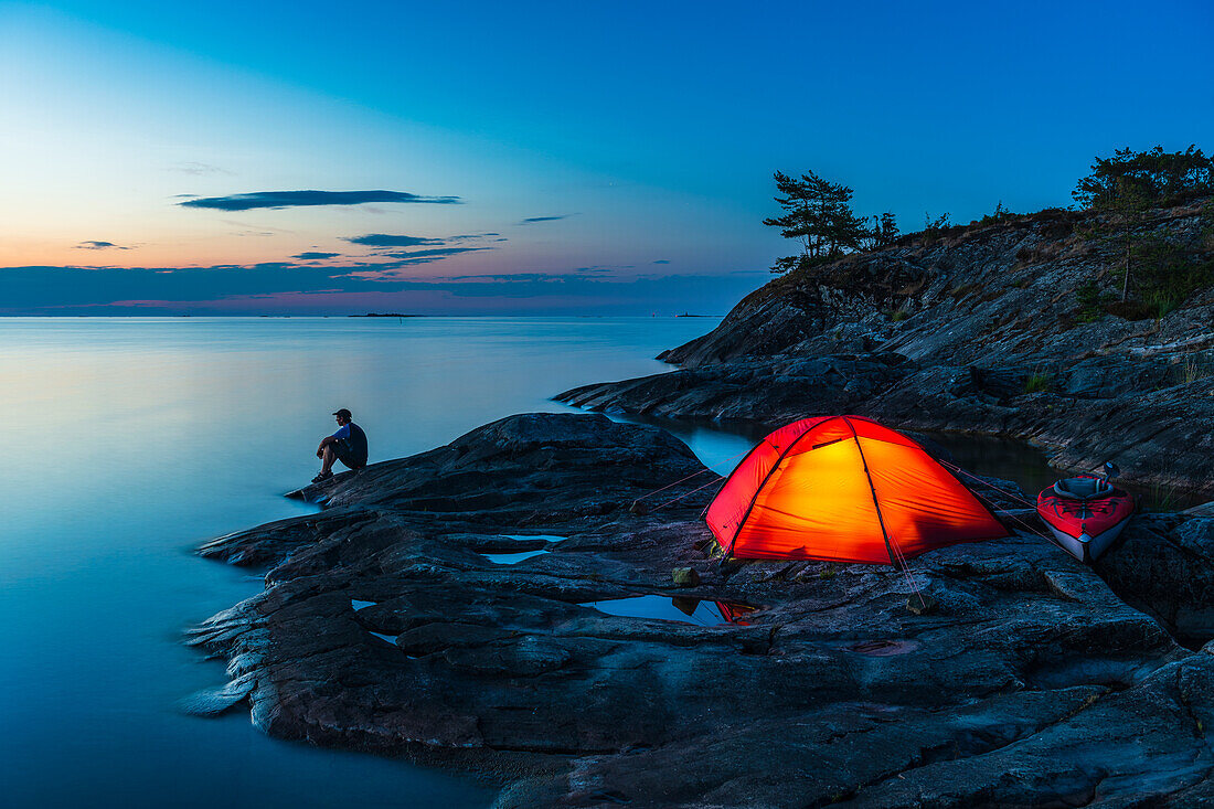 Man sitting by tent on coast