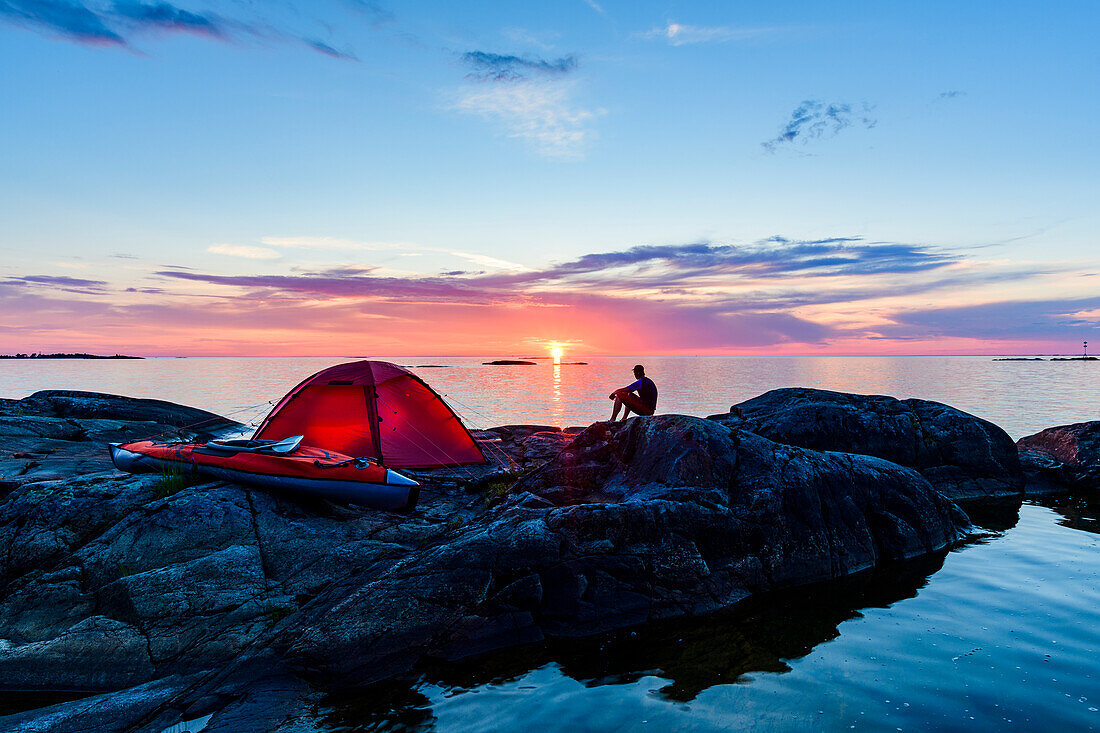 Man sitting by tent at dusk