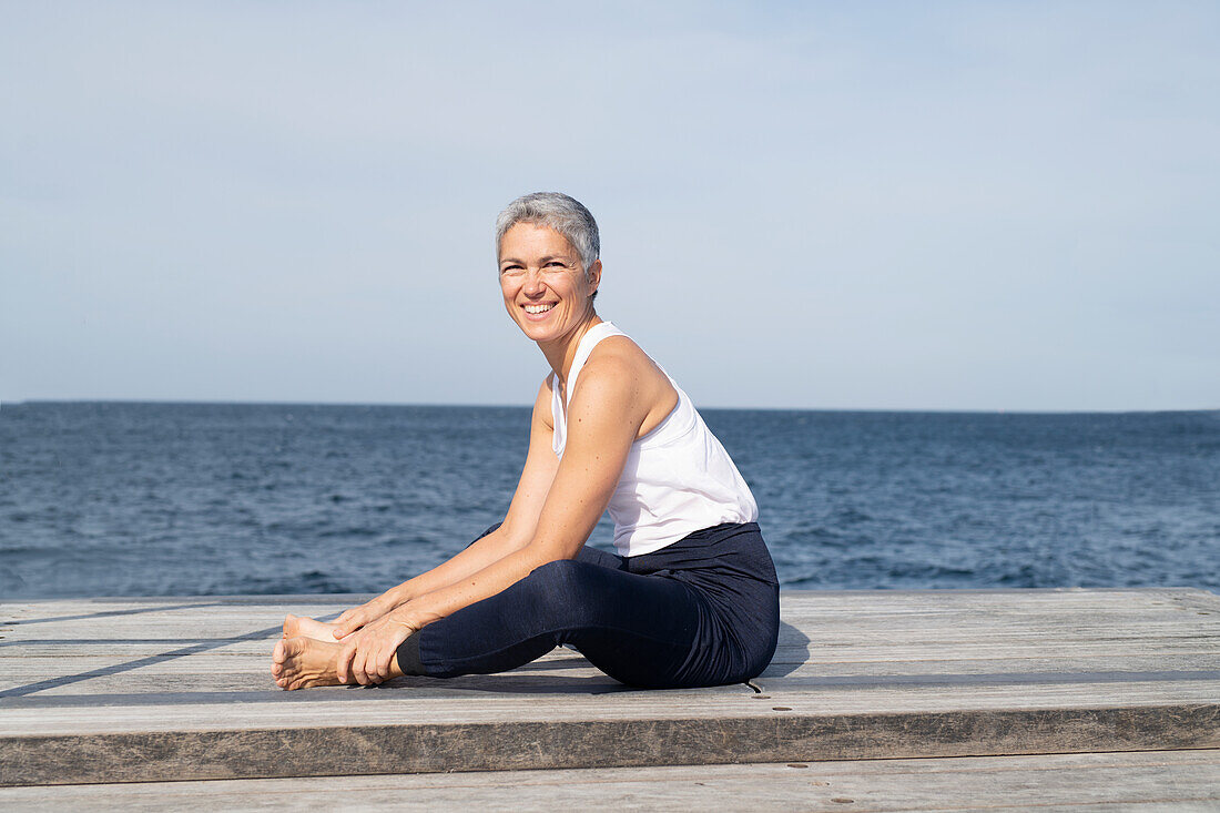 Woman practicing yoga on pier