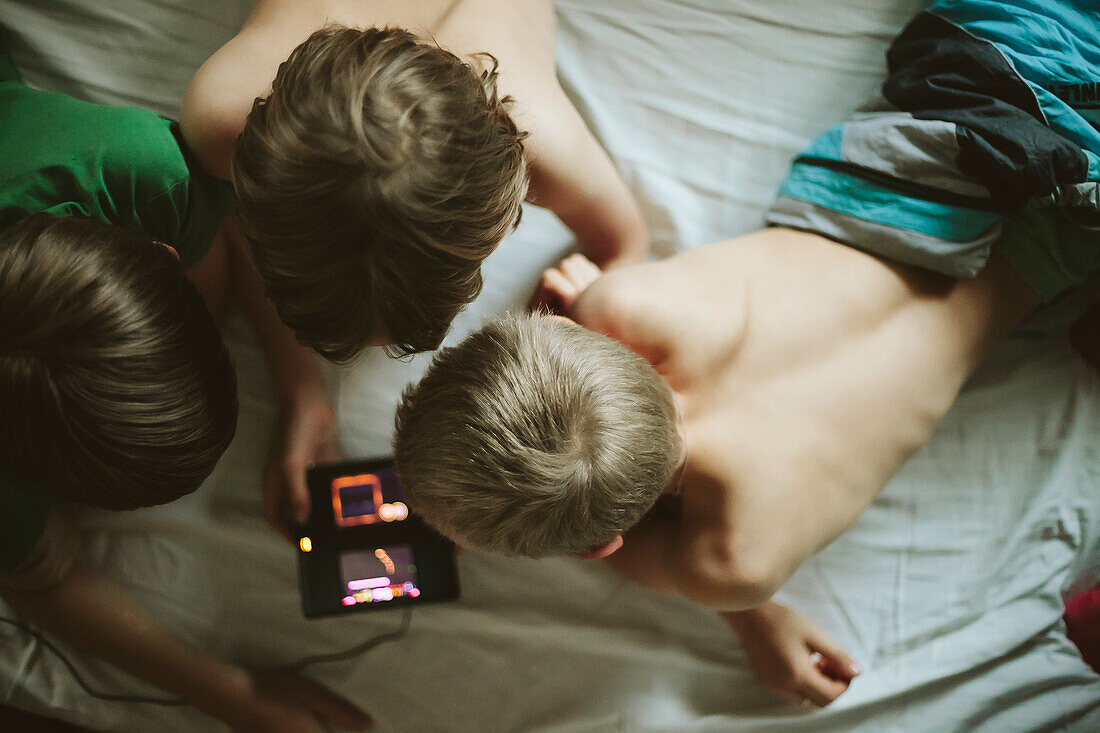 Boys using cell phone in bed