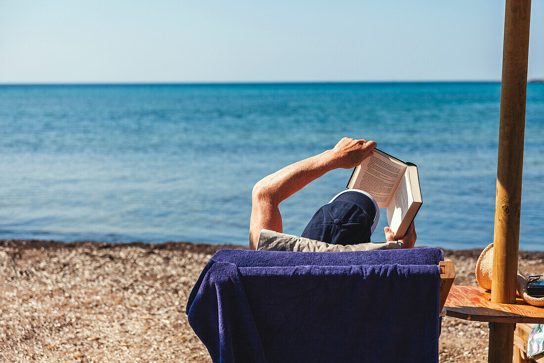 Man reading book on beach