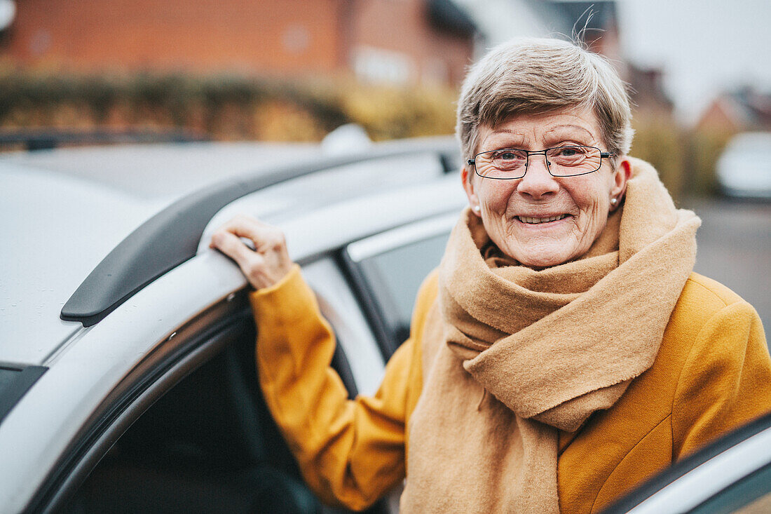 Ältere Frau neben Auto