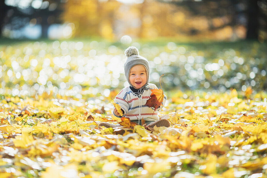 Baby spielt mit Herbstblättern