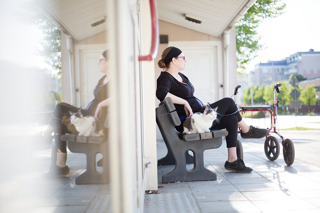 Frau mit Rollator auf einer Parkbank sitzend