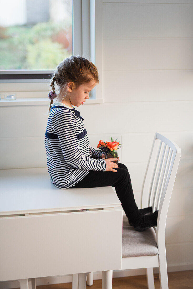 Mädchen sitzt auf Tisch mit Blumen