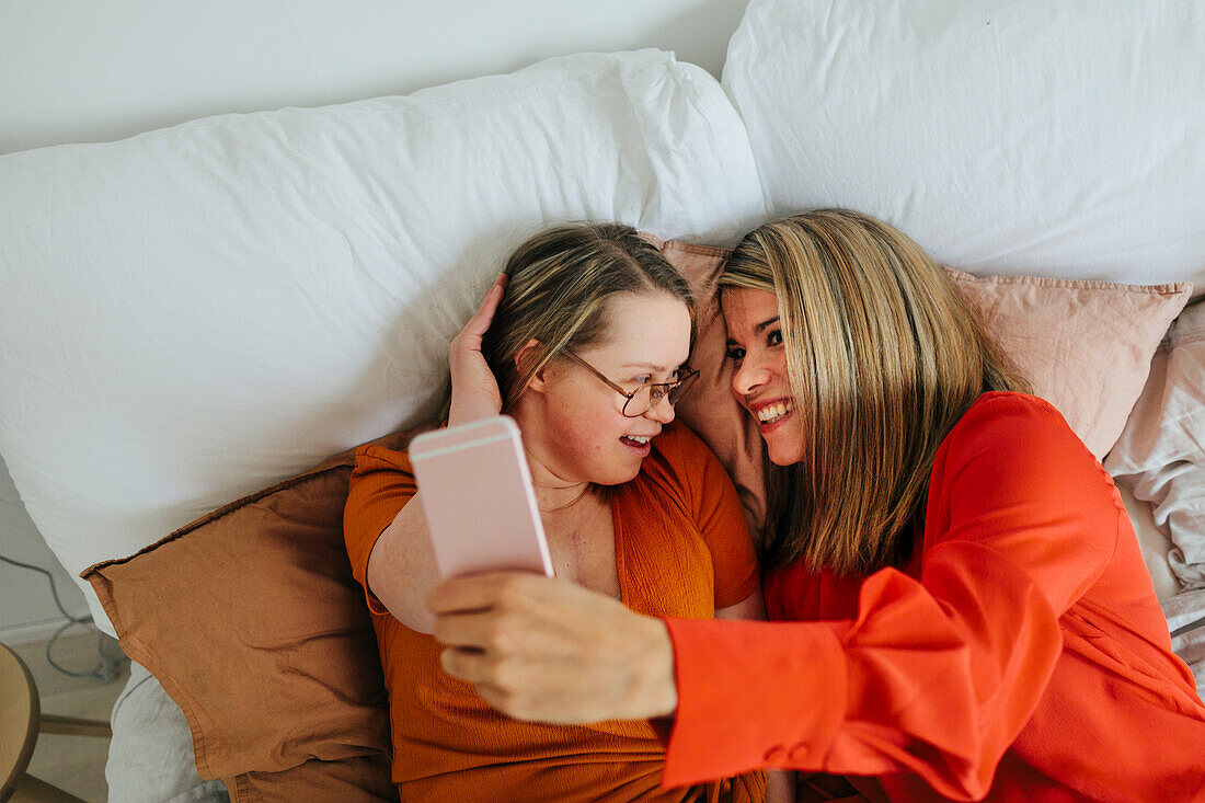 Sisters on bed taking selfie