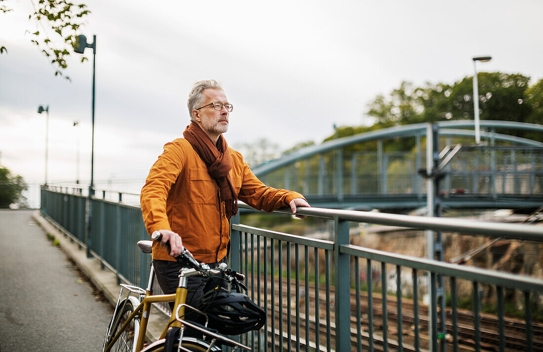 Mann mit Fahrrad auf Brücke stehend