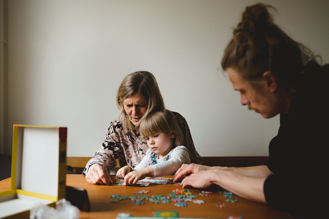 Großeltern und Enkelin beim Puzzeln