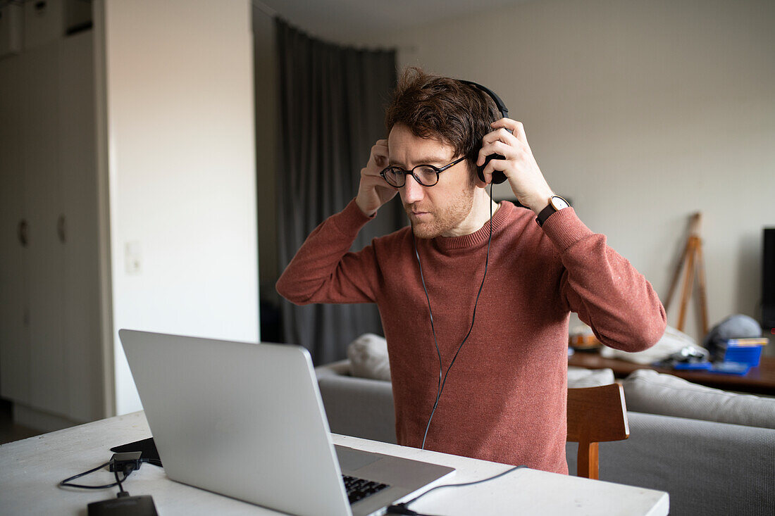 Mann mit Kopfhörern am Laptop