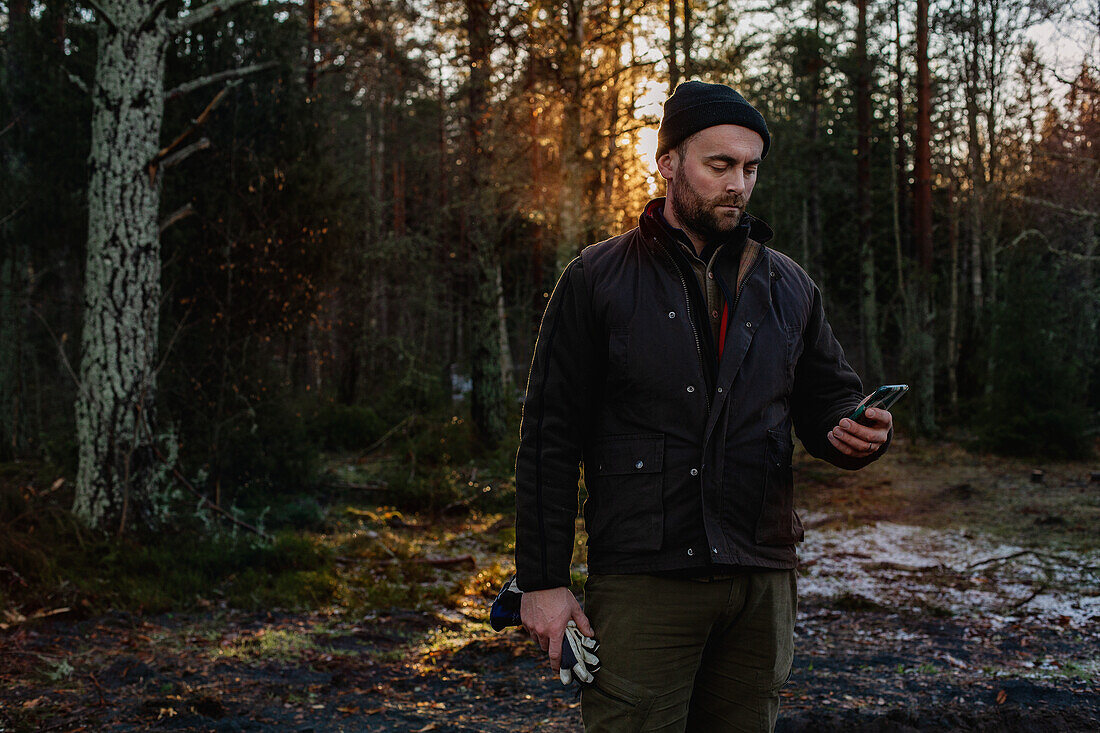 Mann im Wald schaut auf sein Handy